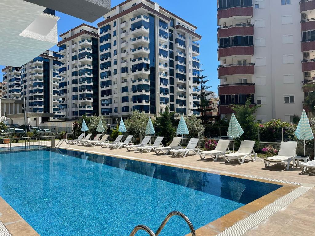 a swimming pool with lounge chairs and buildings at SA Apartments! 1bd Flat 300m to the Beach in Alanya