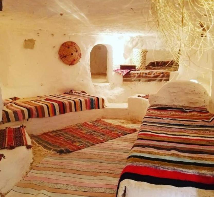 a room with two beds and a rug at Gite Douiret in Ad Duwayrāt