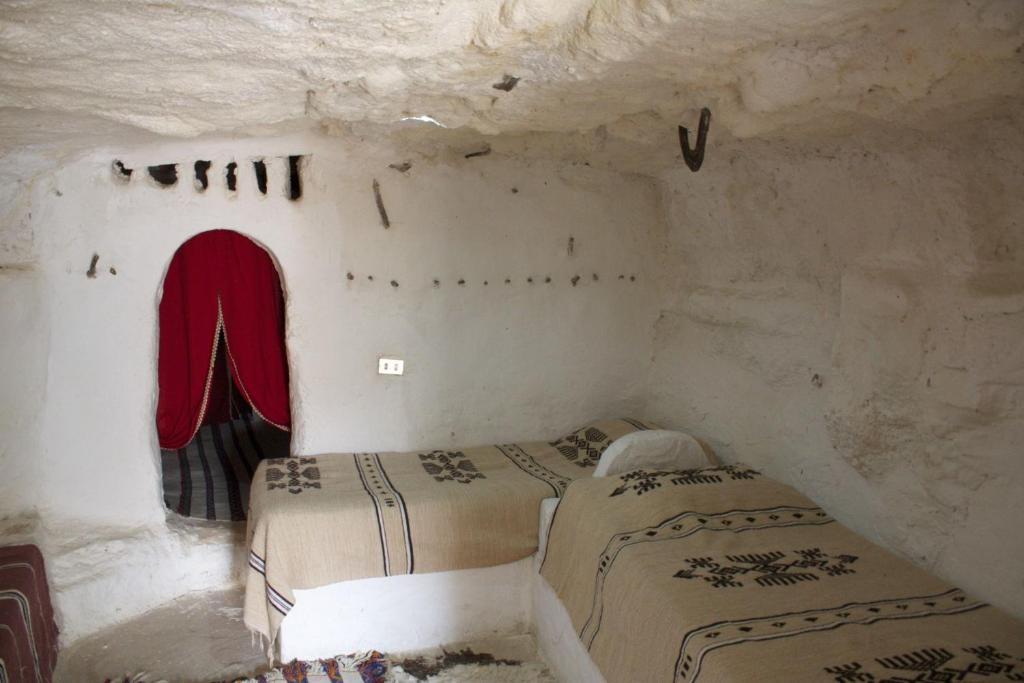 a bedroom with two beds in a stone room at Gite Douiret in Ad Duwayrāt