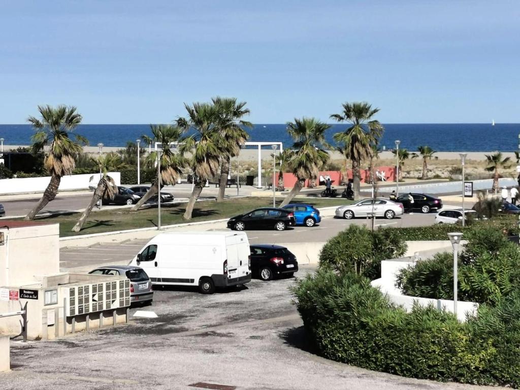 - un parking avec des voitures, des palmiers et l'océan dans l'établissement Résidence Le Neptune - 2 Pièces 4 couchages PORT LEUCATE MAE-8124, à Port-Leucate