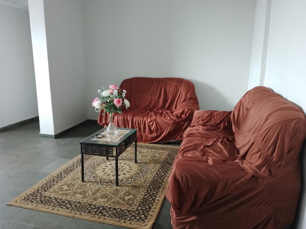 sala de estar con sofá y mesa con un jarrón de flores en Quarto em Apartamento no Centro en Campo Grande
