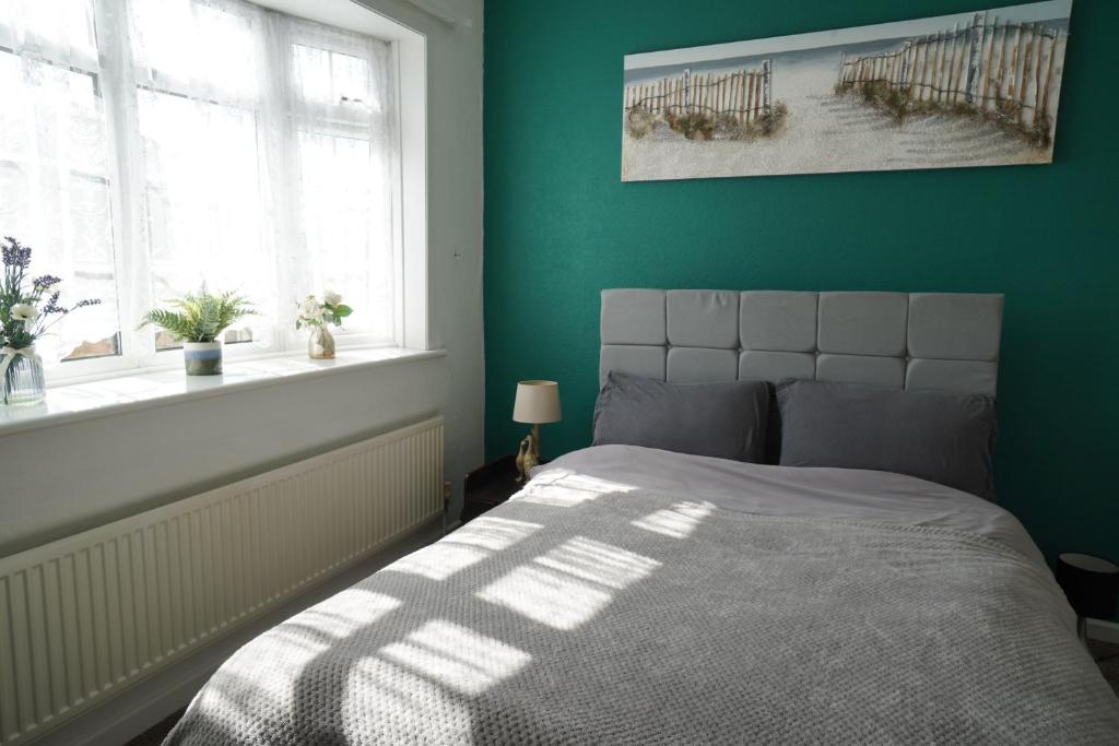 een slaapkamer met een bed en een groene muur bij Llewnodeb in Belvedere