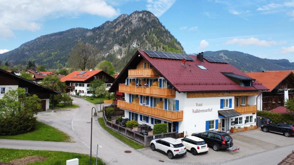 un edificio con techo rojo con coches aparcados delante en Hotel-Garni Kalkbrennerhof, en Pfronten