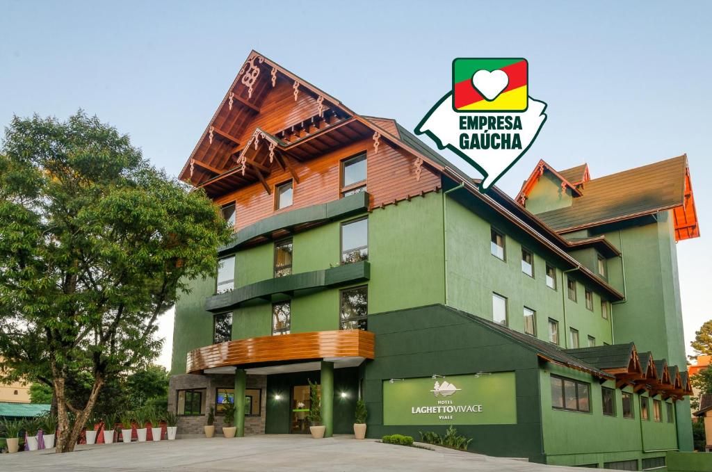 un gran edificio verde con un cartel. en Hotel Laghetto Viale en Gramado