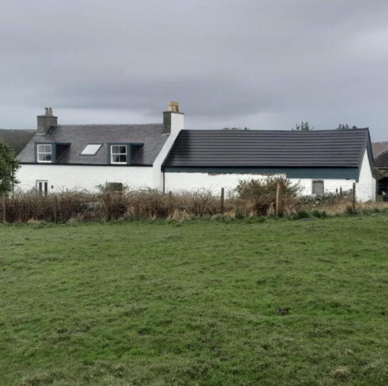 una casa blanca con un campo delante en ISLE OF GIGHA FARM HOUSE en Ardminish