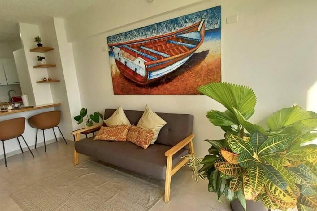 soggiorno con divano e dipinto di una barca di Ocean View. Acogedor Apartamento frente al mar a Porlamar