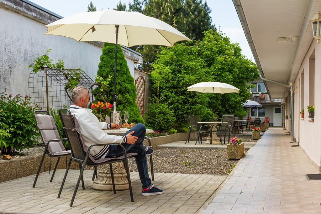 a man sitting in a chair under an umbrella at Apartmany Tereza & free parking in Bratislava