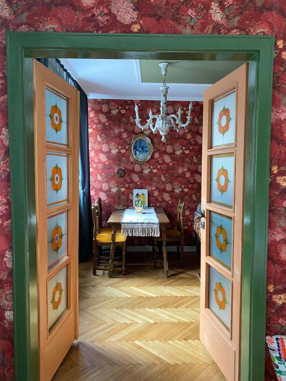 ein Esszimmer mit einem Tisch und einem Kronleuchter in der Unterkunft Vintage Apartment in Pristina