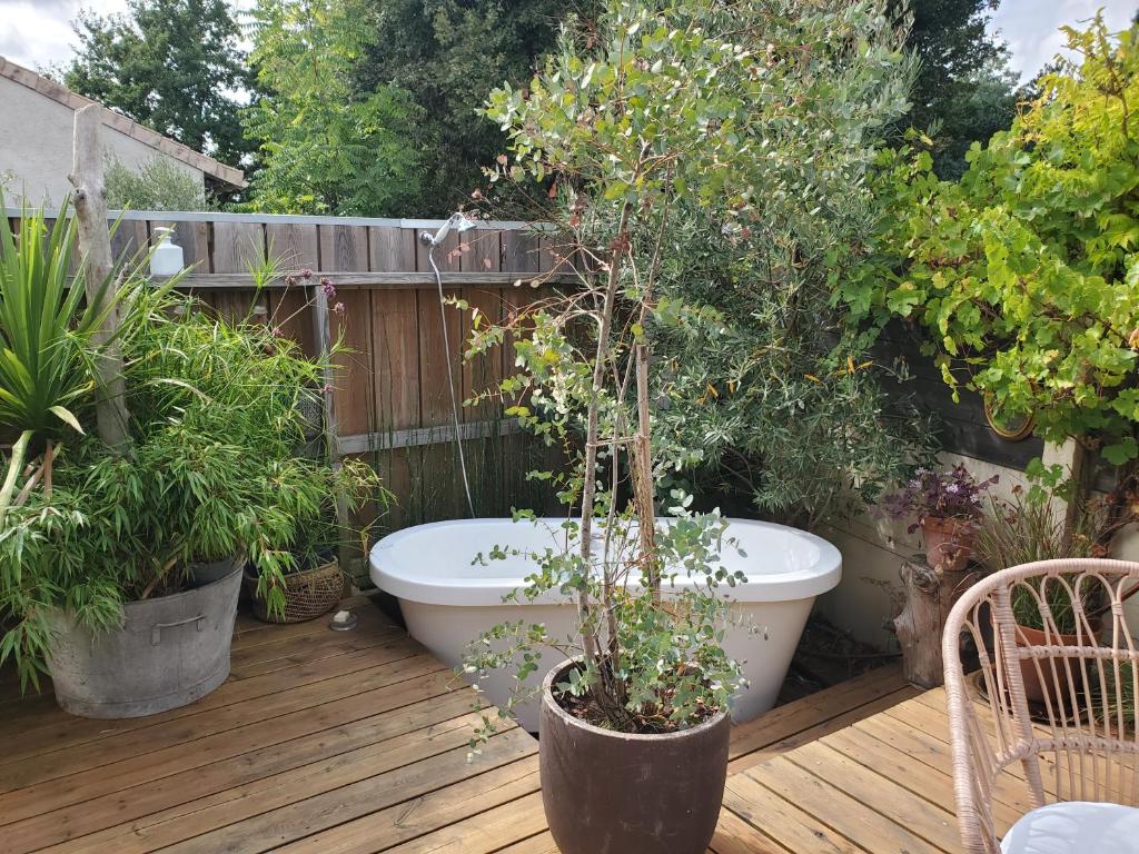 un jardin avec une baignoire sur une terrasse avec des plantes dans l'établissement Jolie maison en bois climatisée Proche Lac&Océan, à Hourtin