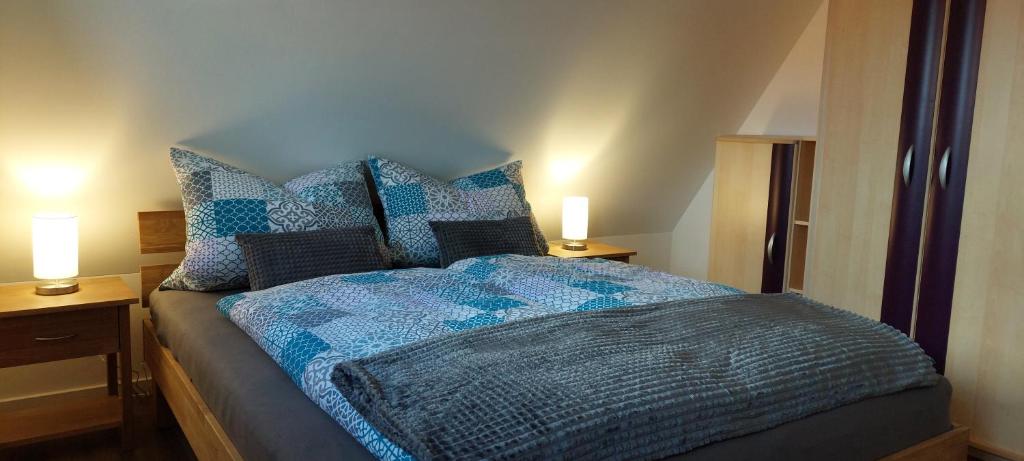 a bed with a blue comforter and two lamps on tables at Ferienwohnungen Urlaubsglück in Kurort Gohrisch