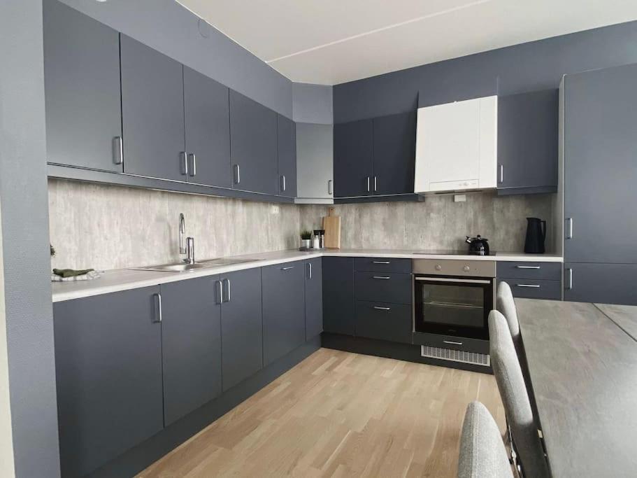 una cocina con armarios azules y una mesa con sillas en Nydelig selveier leilighet med gratis parkering på stedet, en Alta
