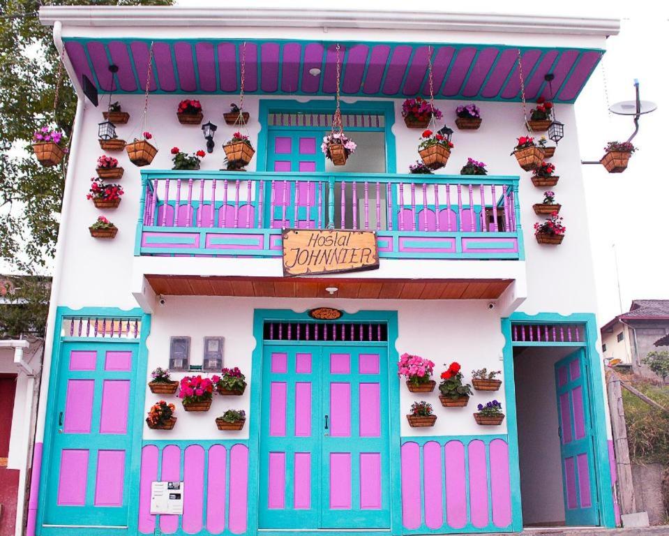 Una casa con puertas azules y rosas y plantas en macetas. en Hostal Johnnier, en Salento