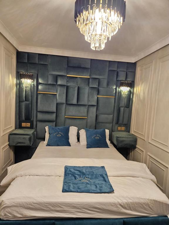 een slaapkamer met een groot bed met blauwe kussens en een kroonluchter bij Miriam Studio in Boekarest