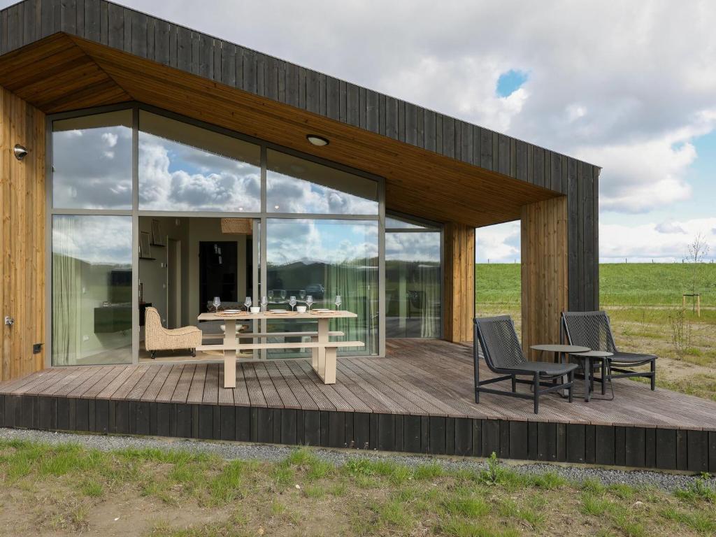 een glazen huis met een tafel en stoelen op een terras bij Beautiful holiday home with garden in Wissenkerke