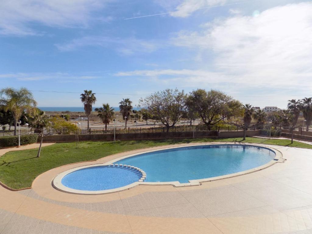 einen Pool in einem Park mit Bäumen und dem Meer in der Unterkunft Playa Ribera MED007 in La Estación