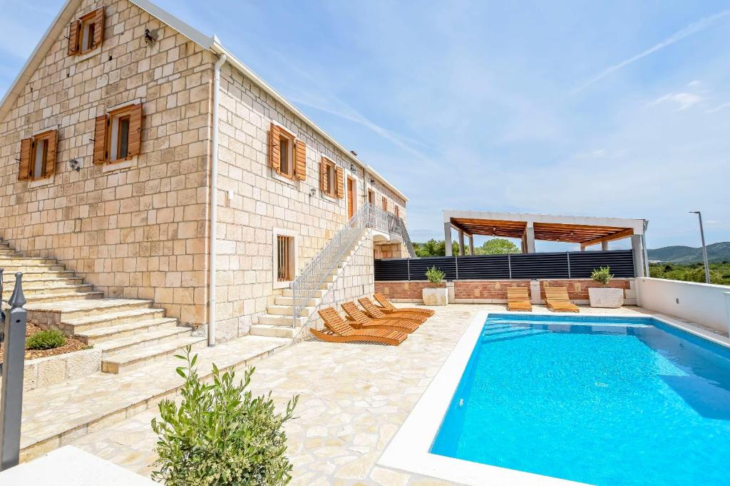 een huis met een zwembad naast een gebouw bij Villa Grgo in Rogoznica