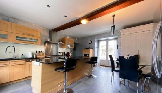 une cuisine avec des armoires en bois et une table et des chaises dans l'établissement Maison de caractère en habitat partagé, à Tourlaville