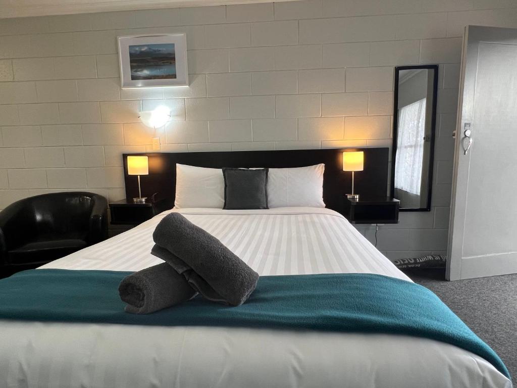 a bedroom with a large bed with two pillows on it at Kensington Motel in Whangarei