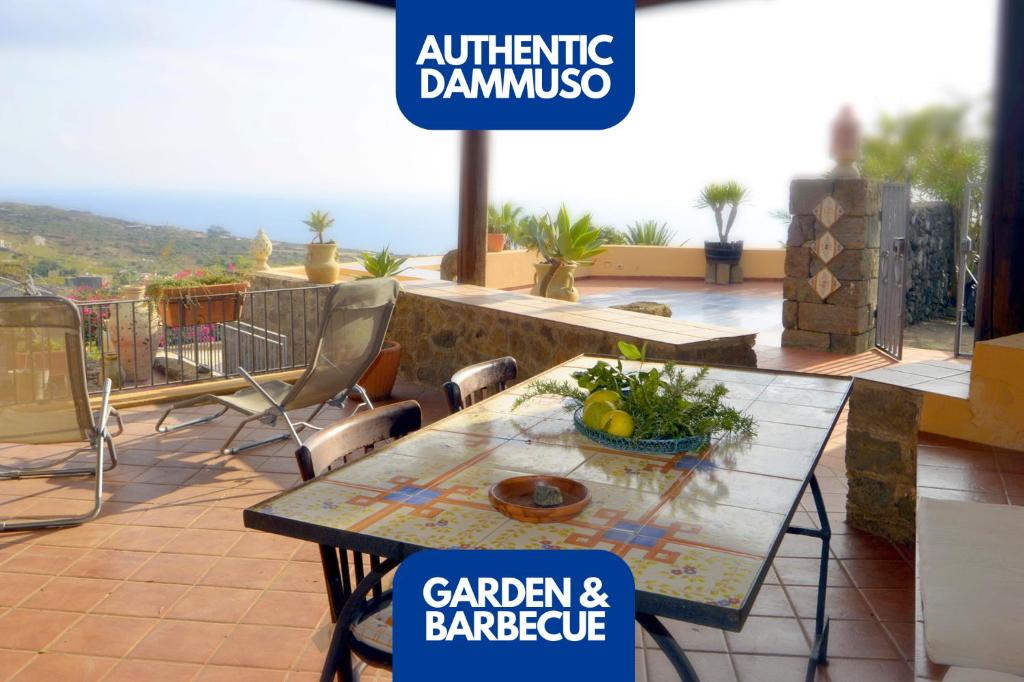 een patio met een tafel en stoelen op een balkon bij Sea View, Nature & Barbecue - Authentic "Dammusi" in Pantelleria