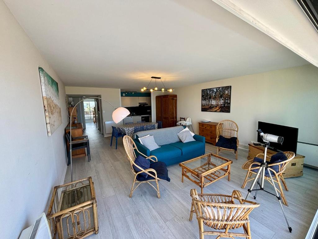 un salon avec un canapé bleu et des chaises dans l'établissement Appt traversant vu Mer et Dunes avec Garage, à Le Touquet-Paris-Plage