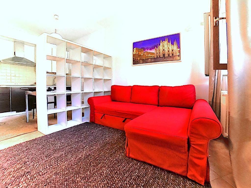 um sofá vermelho numa sala de estar com uma mesa em L' appartamento sul Naviglio em Milão