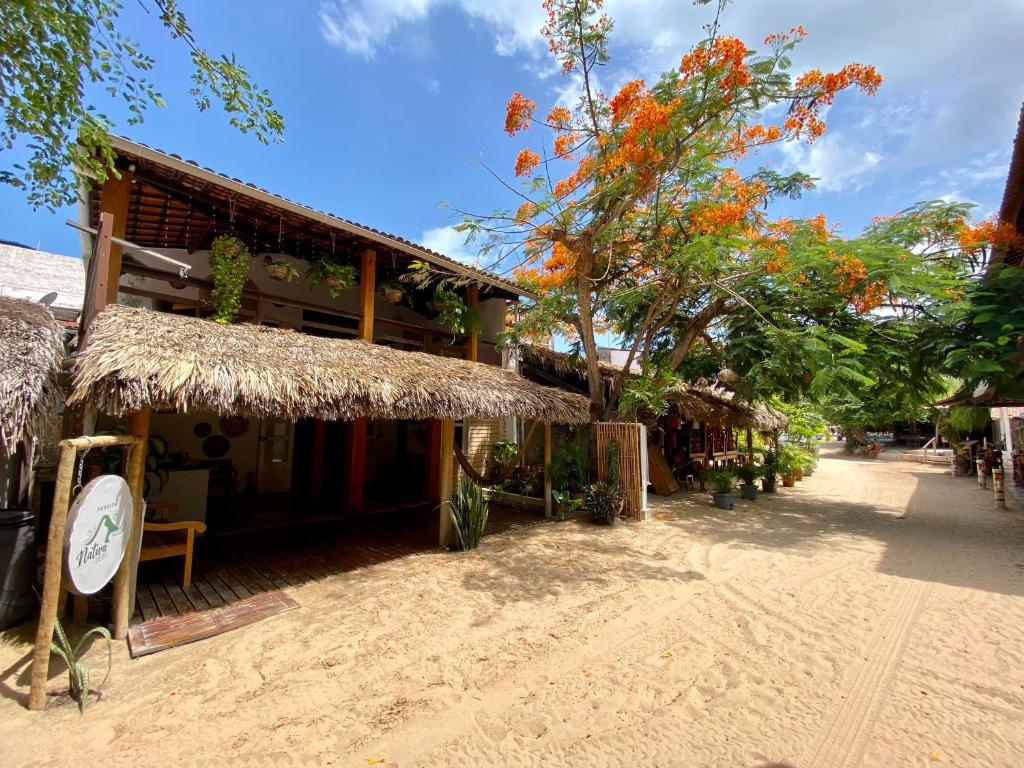 a building with a straw roof next to a street at Pousada Nativa Jeri in Jericoacoara