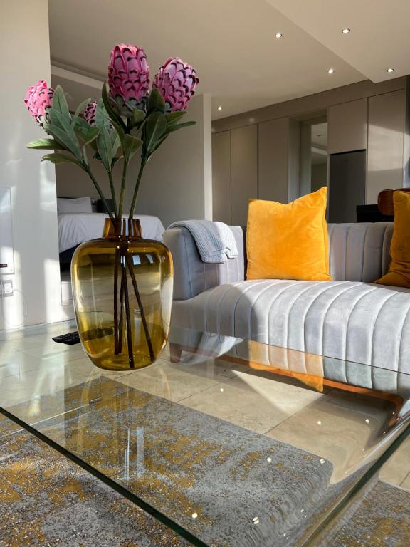 un jarrón con flores sobre una mesa de cristal en la sala de estar en The Franklin Luxury Apartments en Johannesburgo