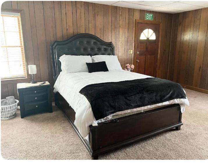 a bedroom with a large bed and a wooden wall at Queen Suite - Indoor Hot Tub - WiFi in Atlanta