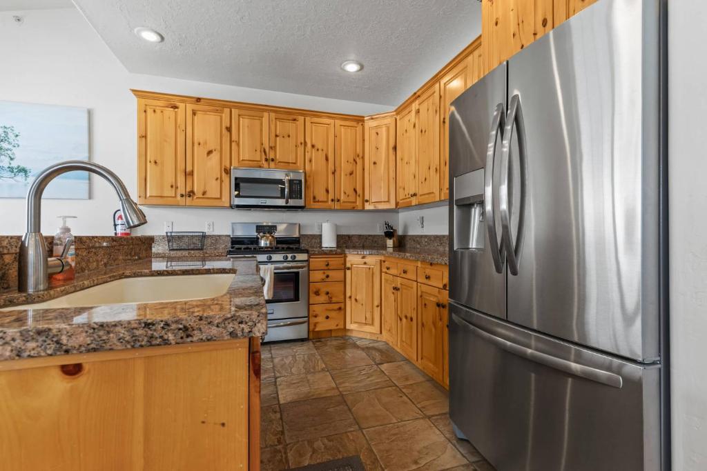 kuchnia z drewnianymi szafkami i lodówką ze stali nierdzewnej w obiekcie Bear Hollow Village 5519 by Moose Management w mieście Park City