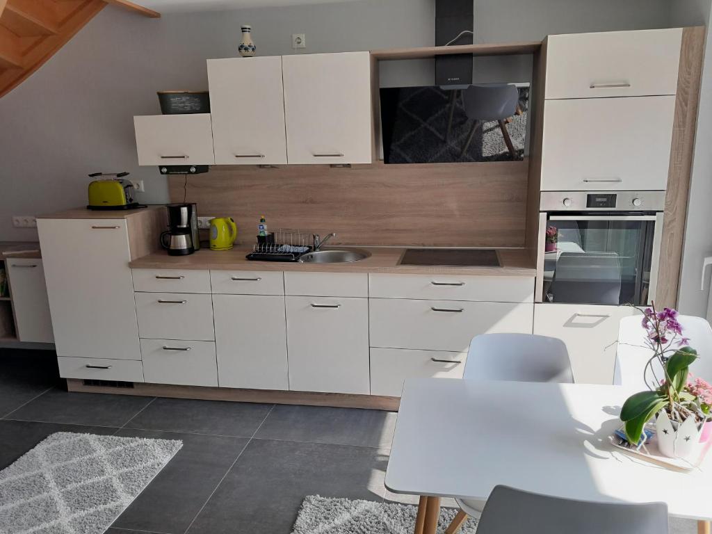 a kitchen with white cabinets and a table at Ferienwohnung Am Bergpark in Bad Muskau