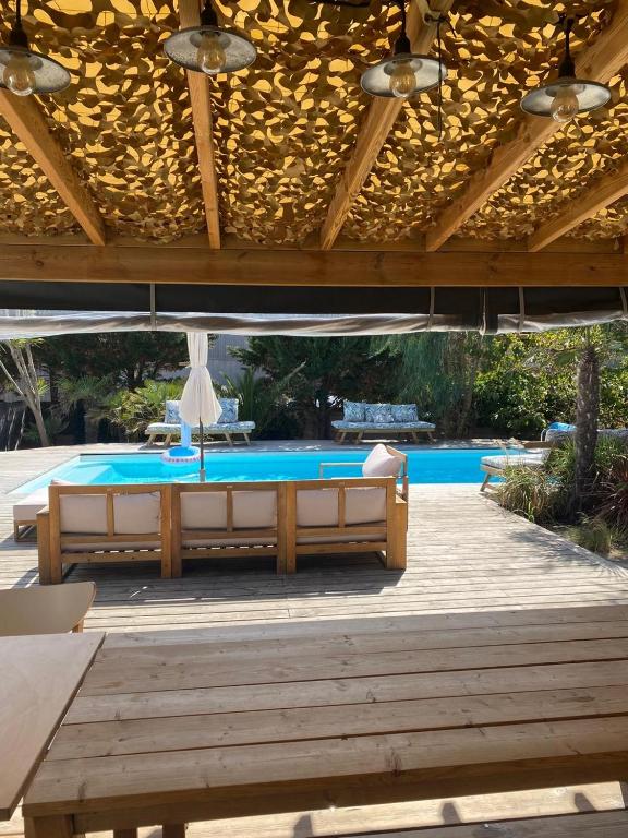 une terrasse avec une piscine, une table et un parasol dans l'établissement Cozy house next to the sea, à Lacanau