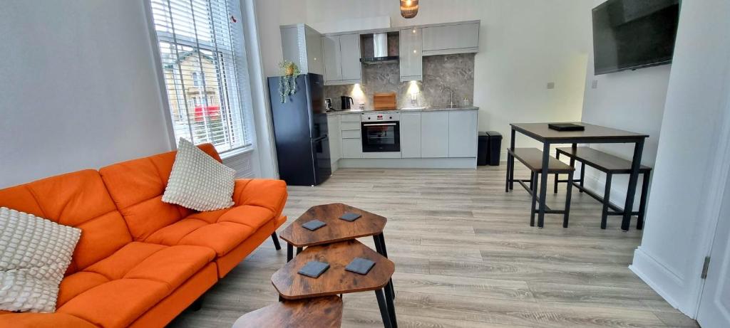 un salon avec un canapé orange et une cuisine dans l'établissement Stylish 1- Bed Apartment Wakefield with Parking, à Wakefield