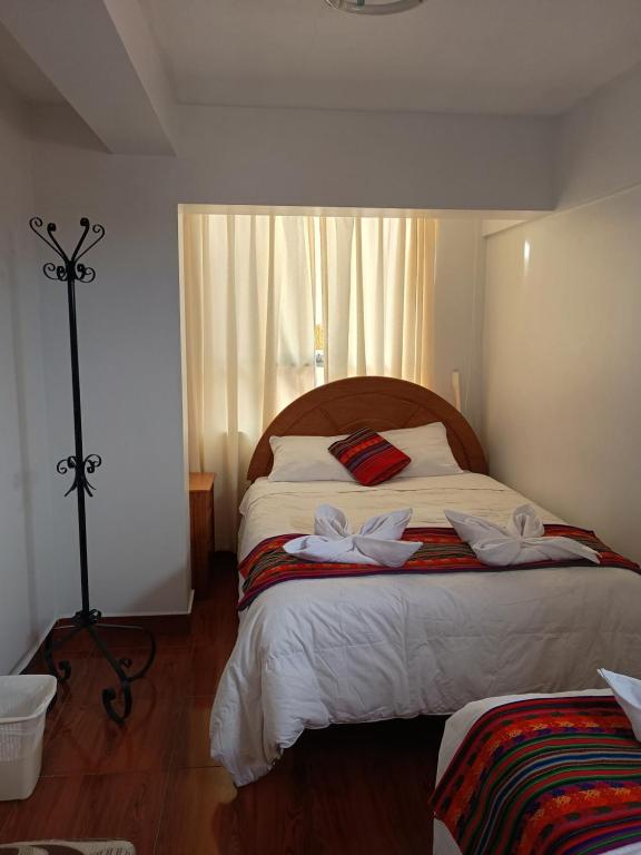 a bedroom with a large bed with two towels on it at Hotel TIKA AYNA Cerca a la plaza de Armas CUSCO in Cusco