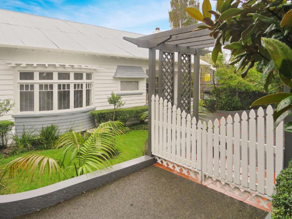 a white picket fence in front of a white house at Island Villa- Waiheke Escapes in Oneroa