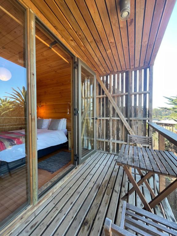 a wooden porch with a bed and benches on a deck at La Ritoqueña Hotel de Playa in Concón