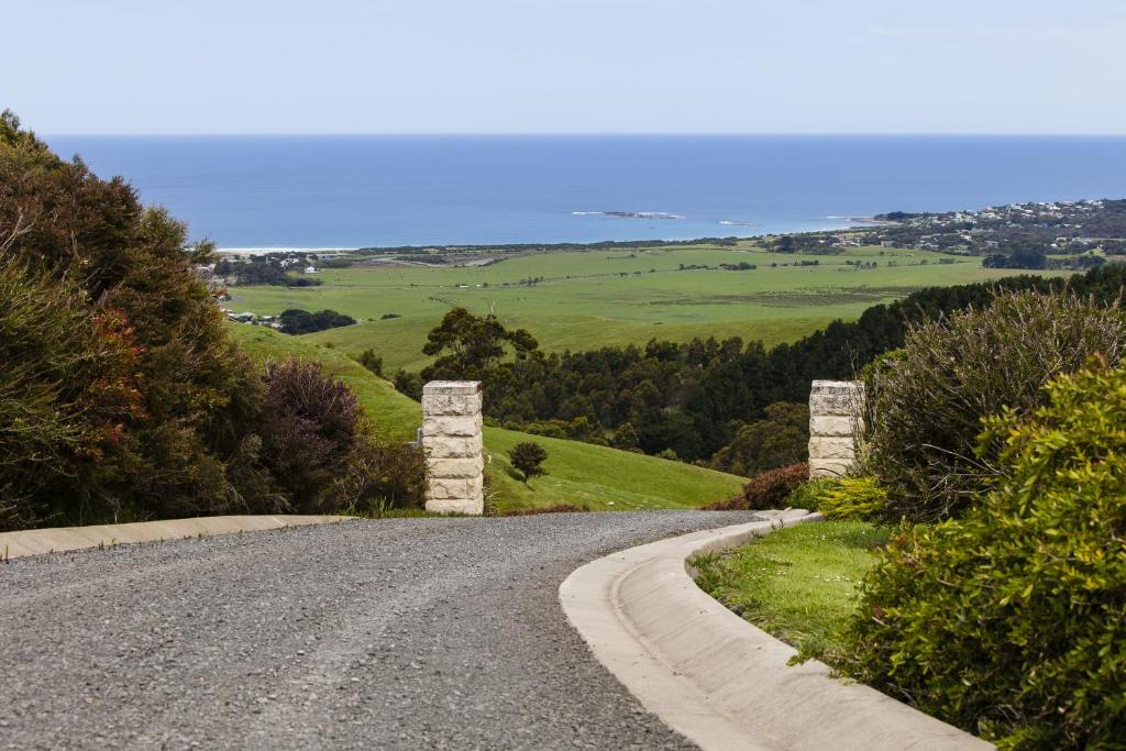 eine Schotterstraße mit zwei Steinsäulen auf einem Hügel in der Unterkunft Glenoe Cottages in Apollo Bay