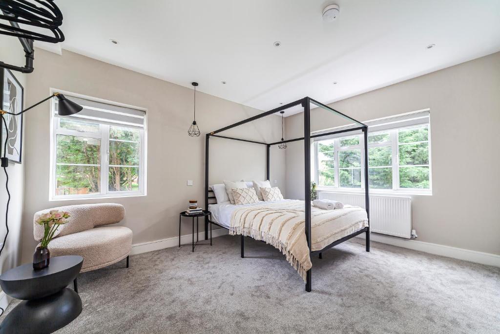 1 dormitorio con cama con dosel y silla en Arte Stays - Newly refurbish stylish 2 bedroom flat - 10 mins walk Wembley Stadium - w parking, en Londres