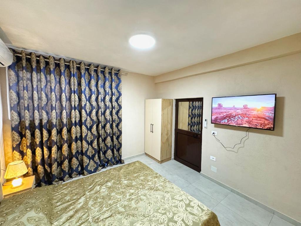 1 dormitorio con TV en la pared y 1 cama en Shkodra Guest House, en Shkodër