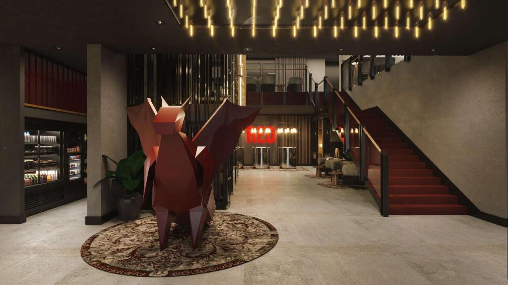 a lobby with a staircase and a statue in the middle at Radisson RED Hotel & Radisson RED Apartments, Kraków in Kraków