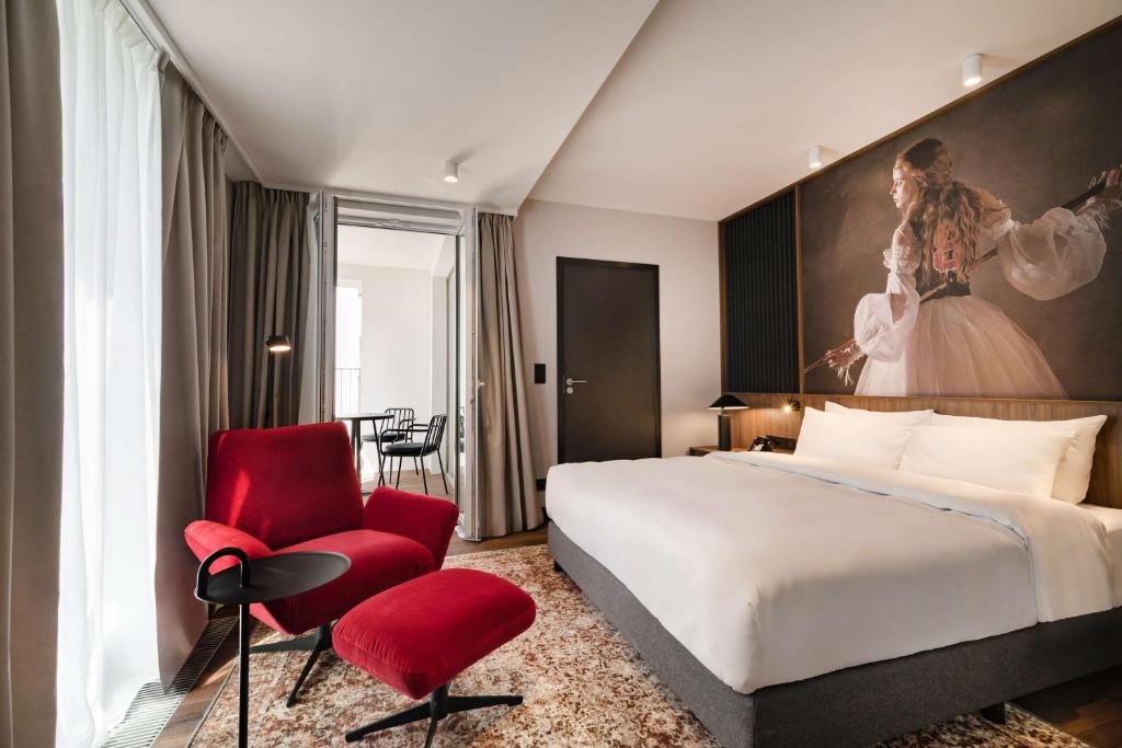 una camera d'albergo con letto e sedia rossa di Radisson RED Hotel & Radisson RED Apartments, Kraków a Cracovia