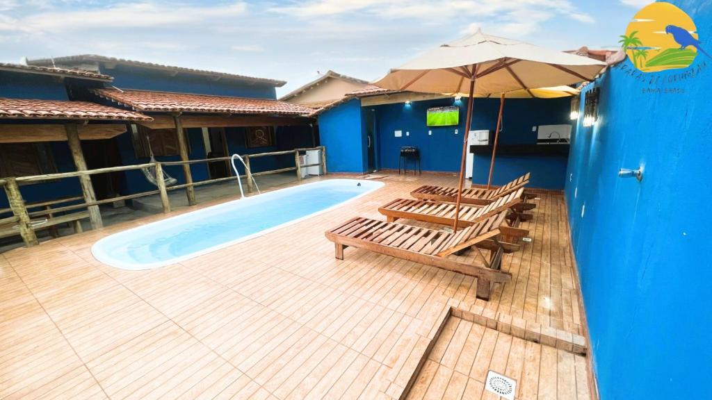 a swimming pool with two chairs and an umbrella at Casa Araras de Corumbau in Corumbau
