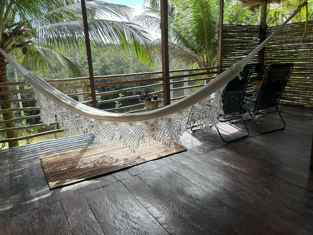a hammock on a balcony with two chairs and palm trees at Ponta Poranga Jungle Lodge in Manaus
