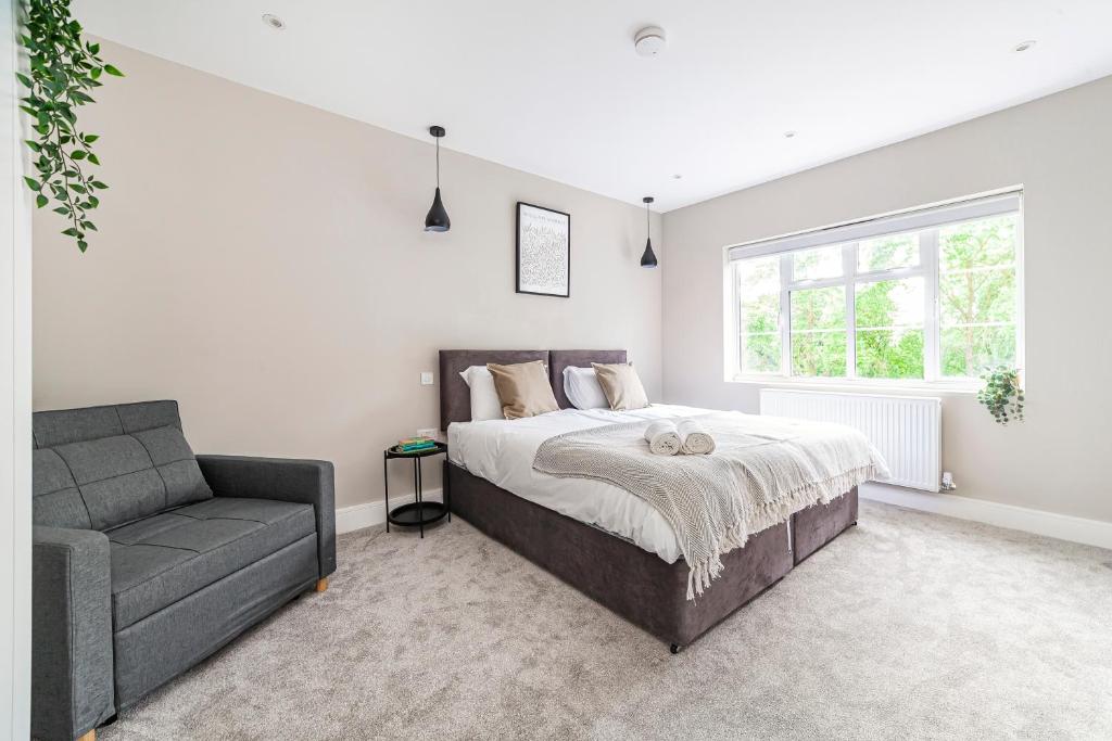 a bedroom with a bed and a couch and a window at Arte Stays - New & Spacious 2 Bedroom Flat - close by Wembley Stadium - Parking in London