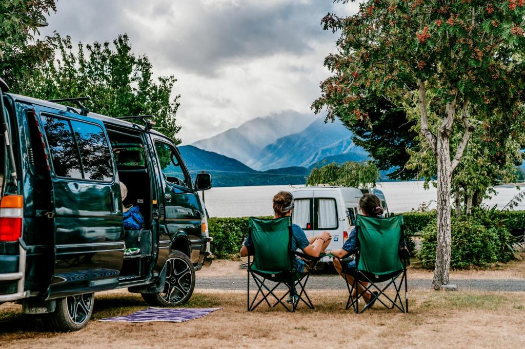 two people sitting in chairs next to a van at Te Anau Lakeview Holiday Park & Motels in Te Anau