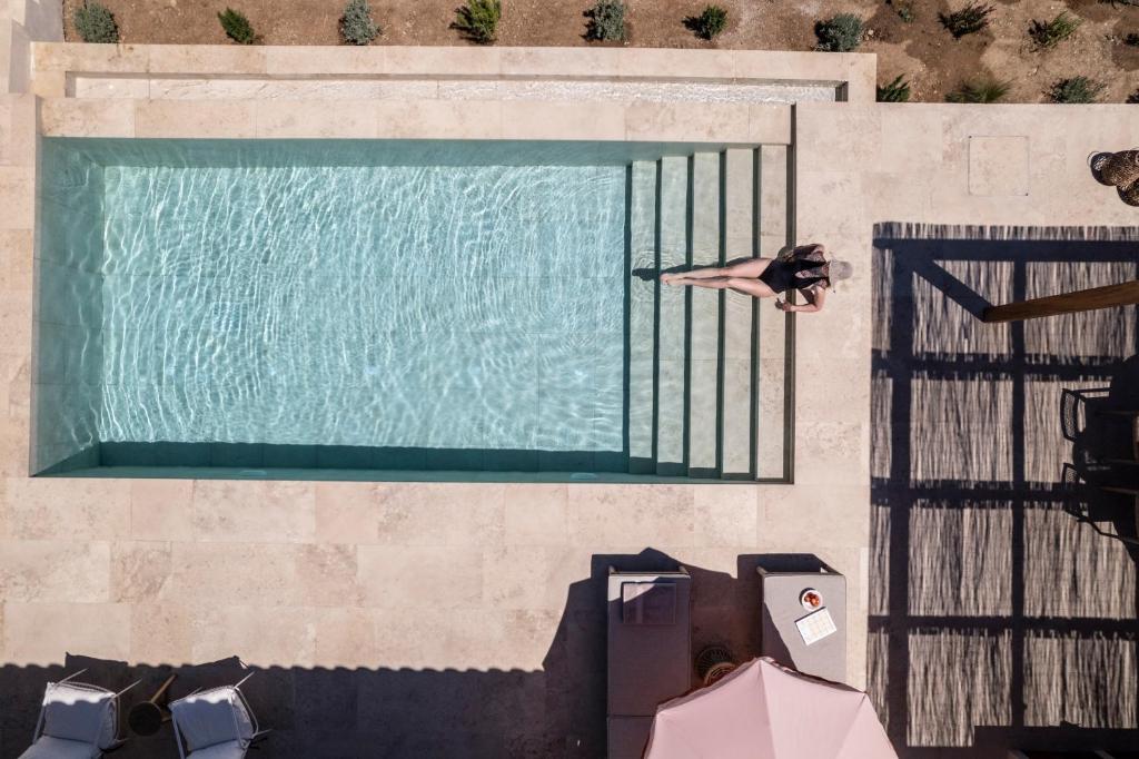 uma pessoa está deitada à beira de uma piscina em Montesea - Luxury Nature Villas em Vasilikos