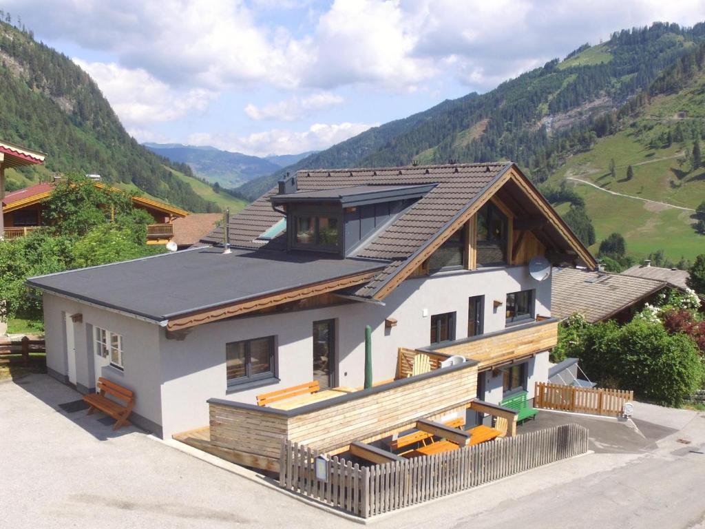 uma casa com um telhado com montanhas ao fundo em Seidlwinkel em Rauris