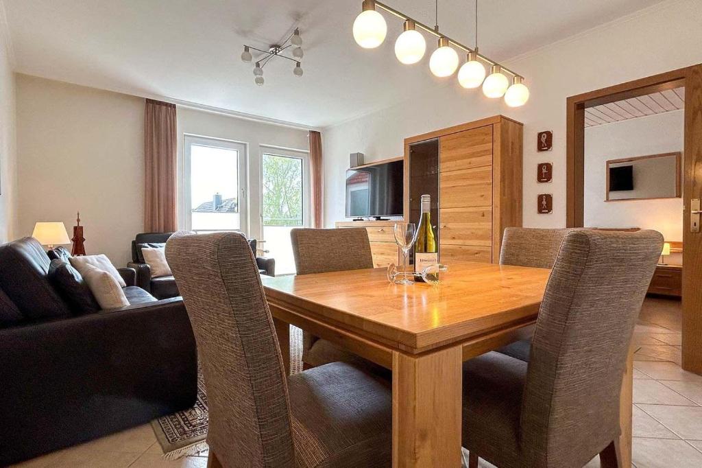 a dining room and living room with a wooden table and chairs at Ferienwohnung-10-mit-Balkon-Garten-Landhaus-Hubertus-Duhnen in Cuxhaven
