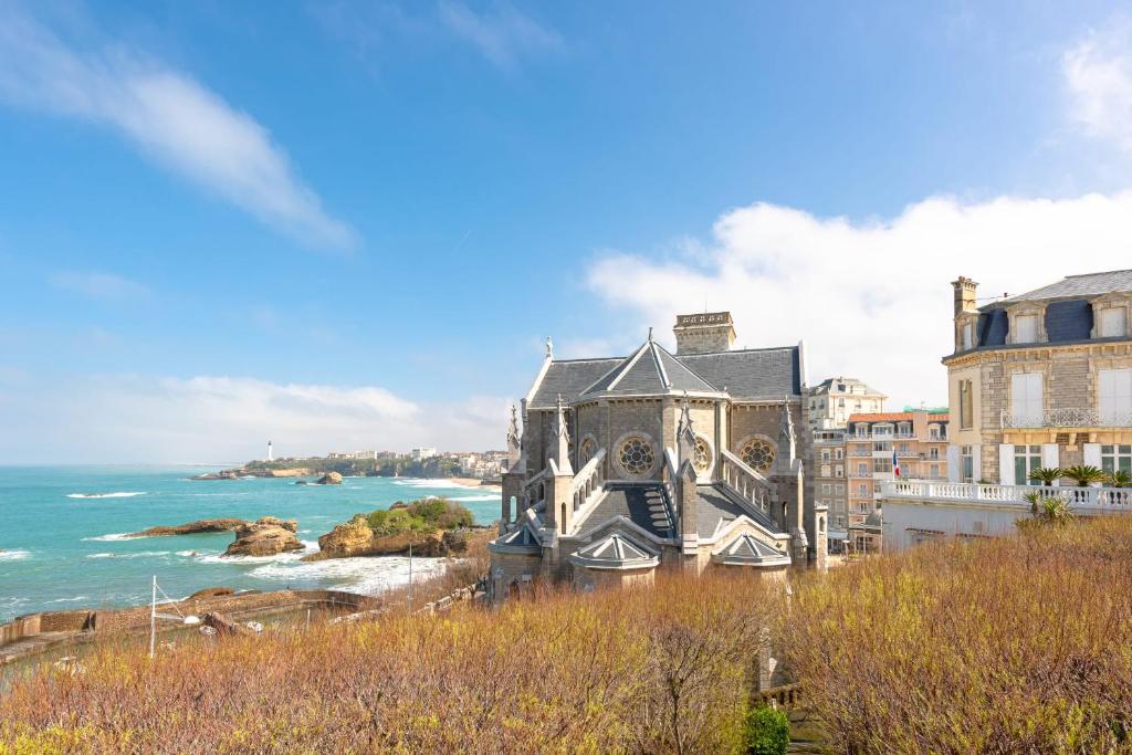 une église sur une colline à côté de l'océan dans l'établissement MOANA KEYWEEK Sea view apartment Biarritz downtown, à Biarritz