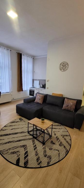 a living room with a black couch and a coffee table at Au coeur du théâtre in Verviers