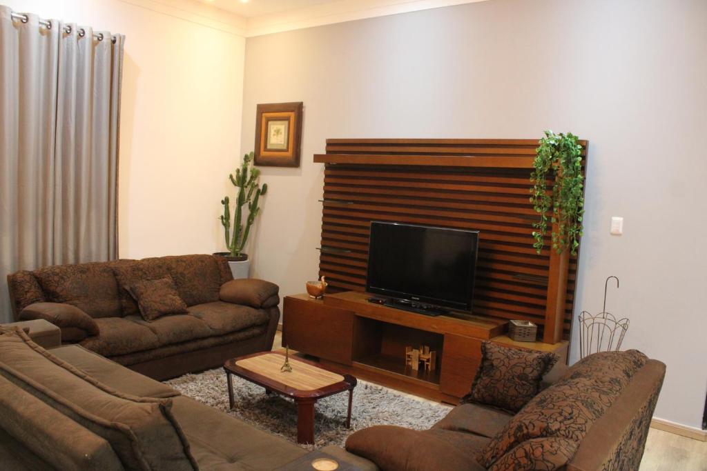 sala de estar con 2 sofás y TV de pantalla plana en Hotel Cristo Rei, en Conceição da Aparecida